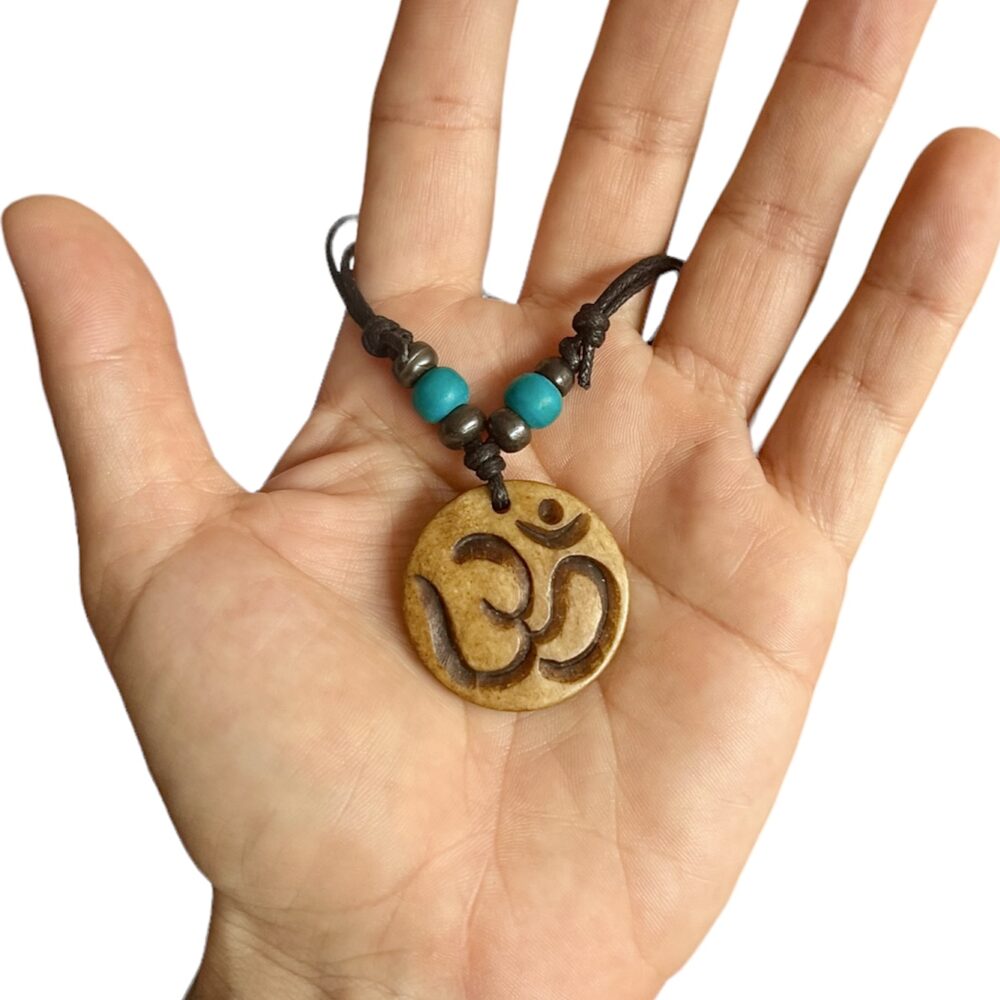 Colgante Amuleto Símbolo Om Hindú mostrado en una mano con fondo blanco